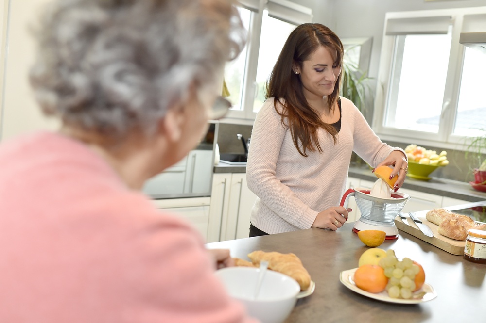 Home helper serving breakfast to elderly woman.jpeg